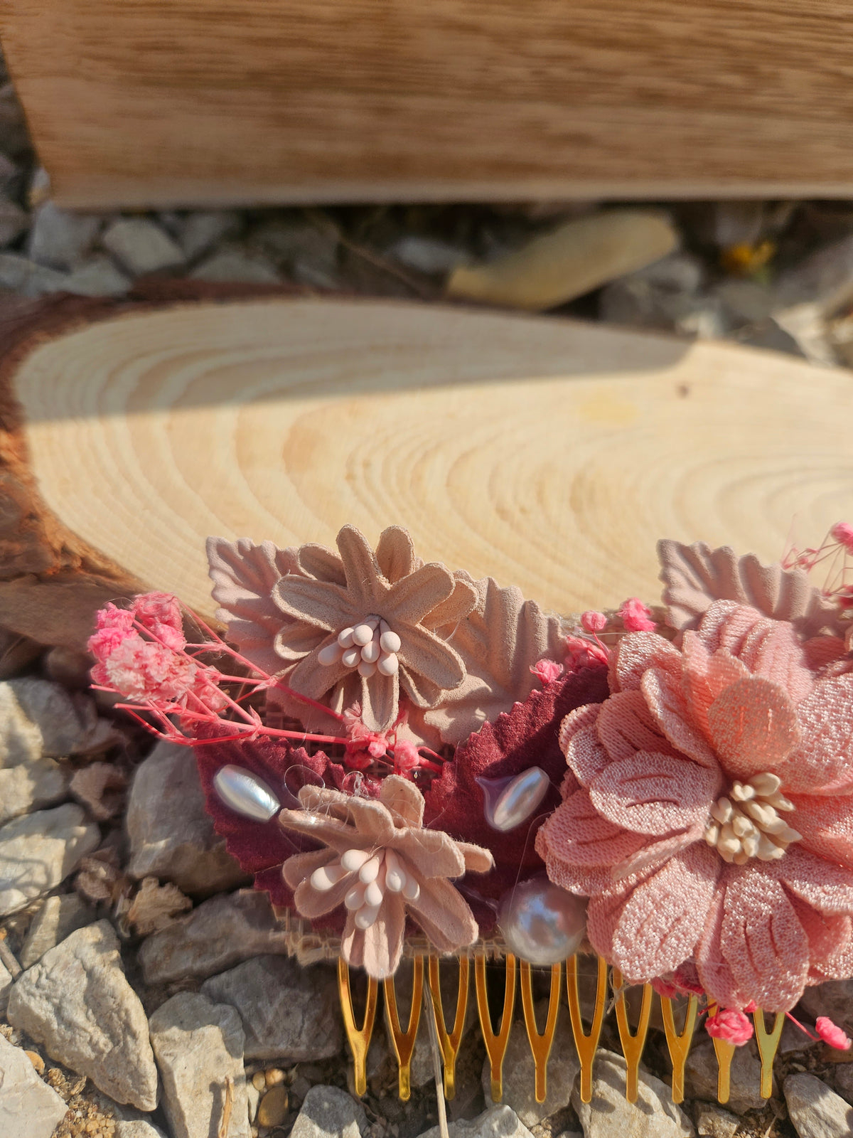 Peina Rosa con flores de tela en tonos rosa, coral y morado, con púas doradas.