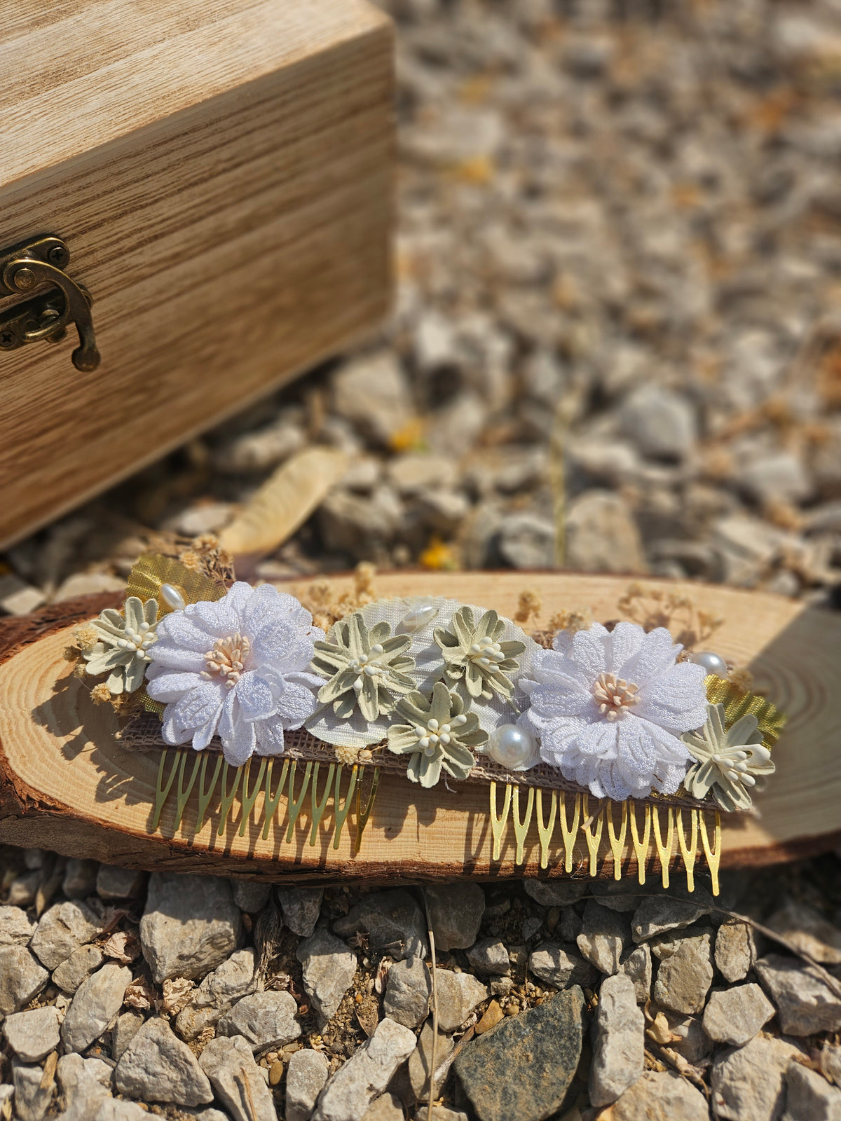 Peine para el cabello con tres flores blancas, hojas doradas y cuentas perladas.