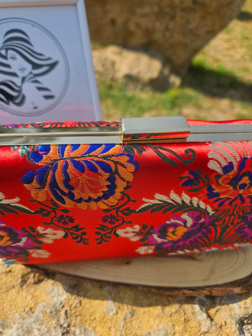 Bolso rojo con bordado floral multicolor y marco/cierre metálico dorado.