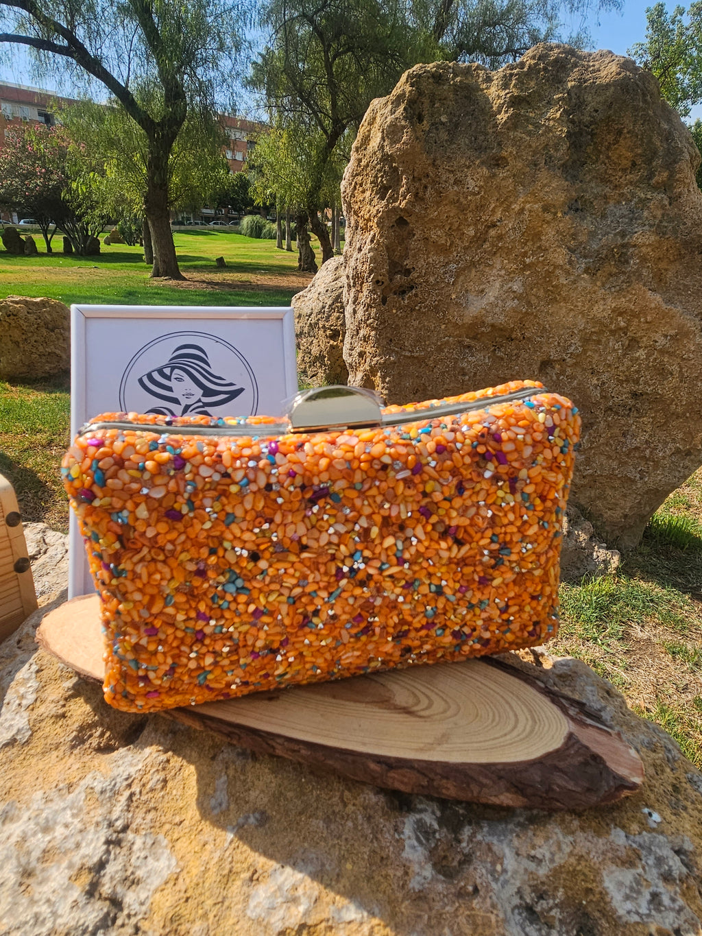 Bolso de cuentas con textura naranaja y asas metálicas, cierre superior.
