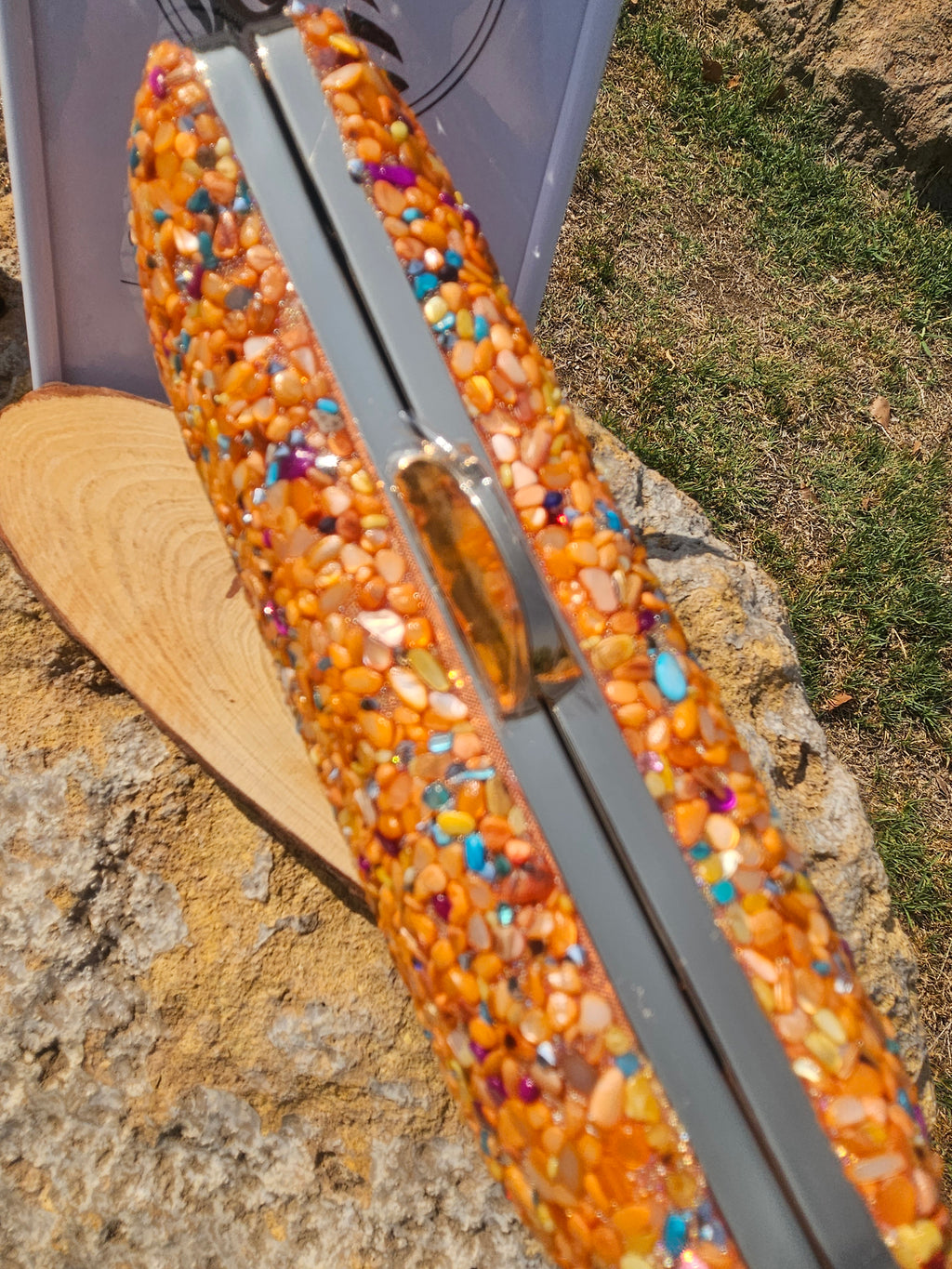 Bolso de cuentas naranjas multicolor con asa metálica alargada, vista lateral.