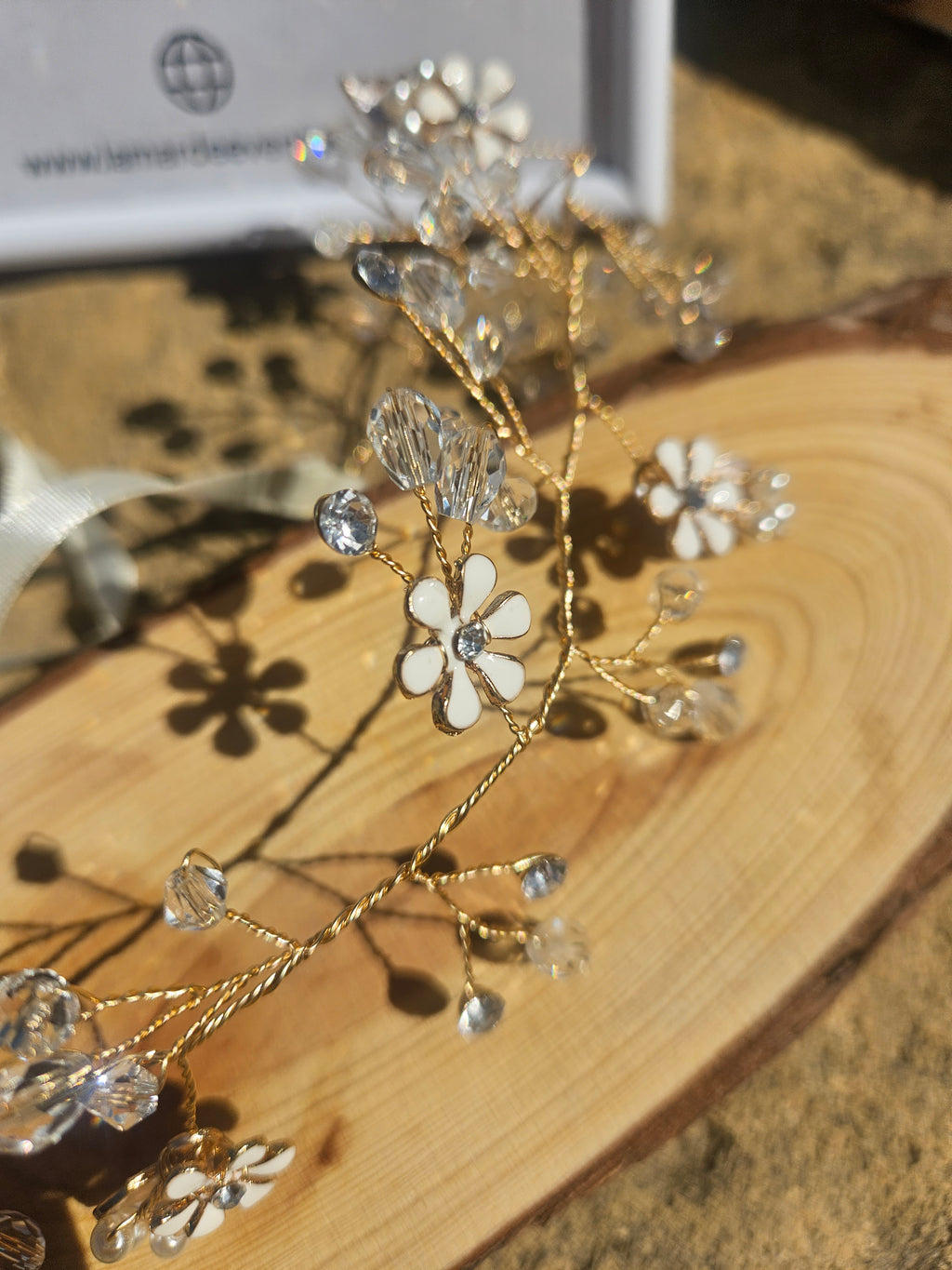Detalle de tiara de novia Kalinda: flores con pedrería y ramitas doradas brillantes