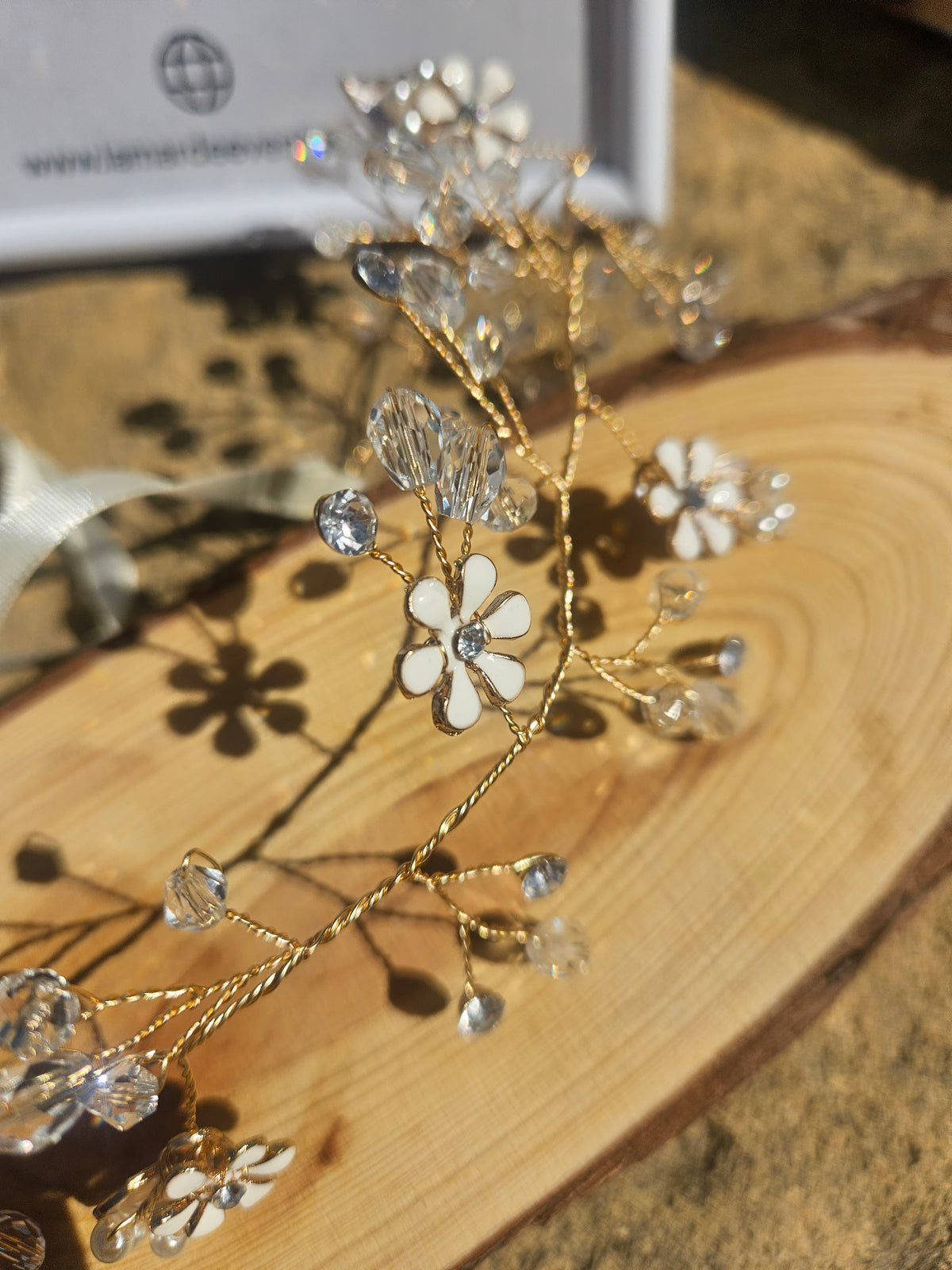 Detalle de tiara de novia Kalinda: flores con pedrería y ramitas doradas brillantes