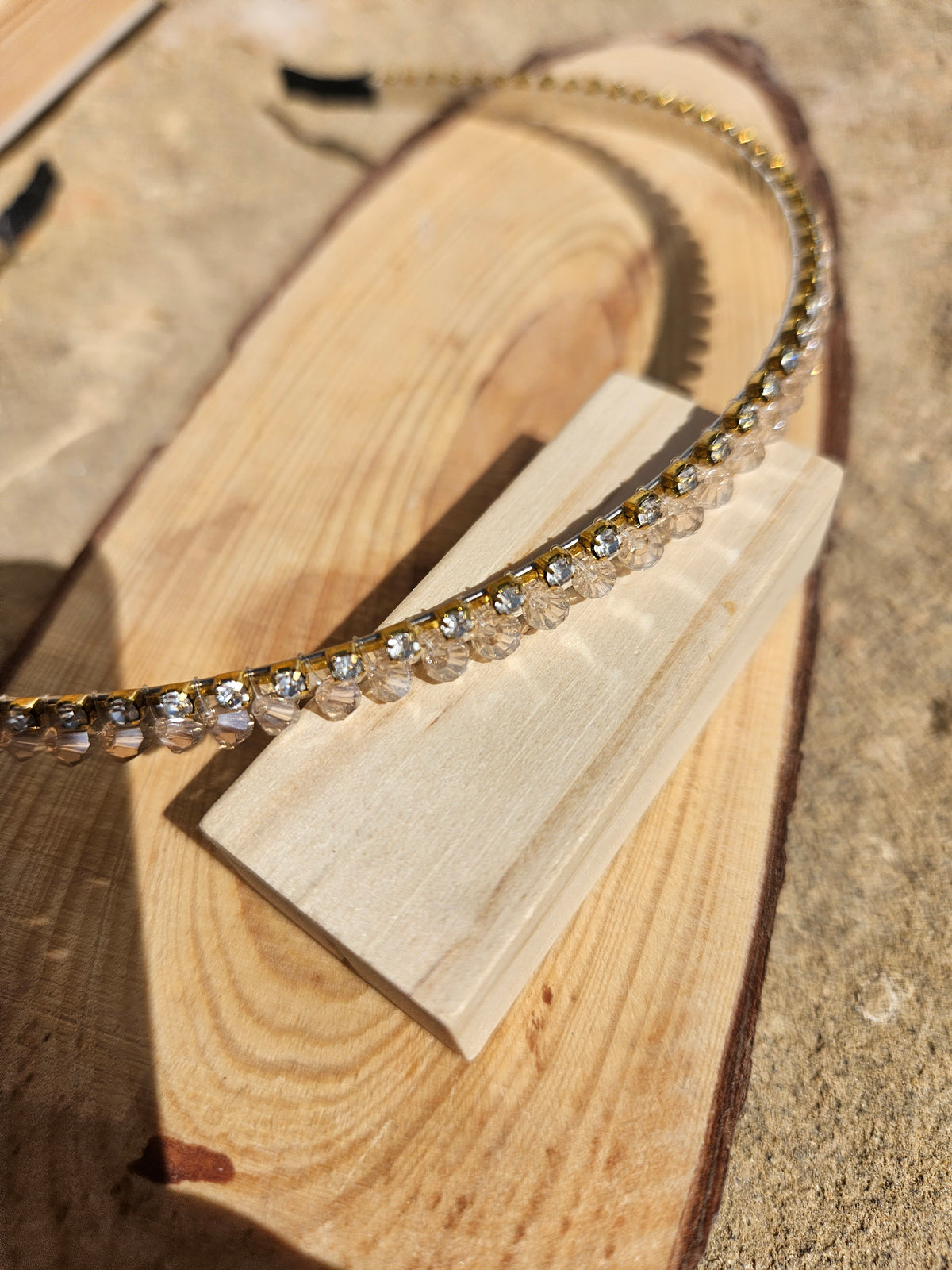 Diadema con pedrería tipo cristal en tono dorado, detalle del borde