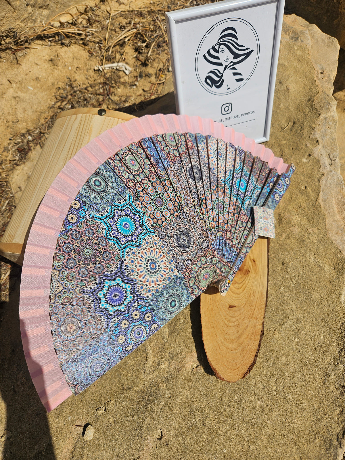 Abanico geométrico rosa abierto con diseño mandala azul y borde rosa