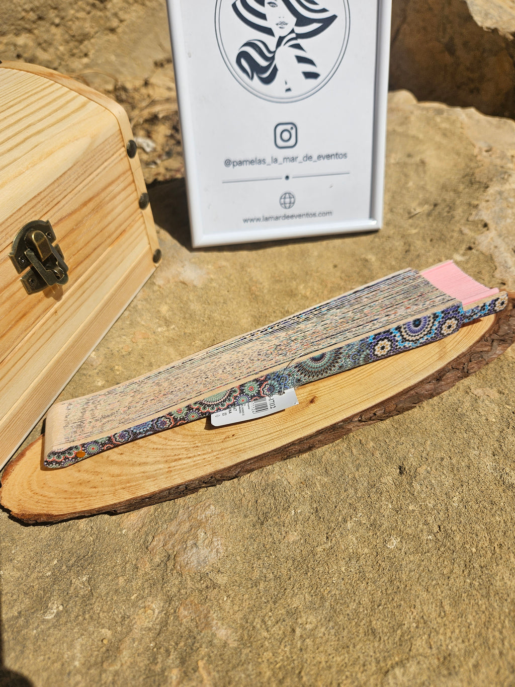 Abanico geométrico rosa plegado con patrón azul, sobre soporte de madera
