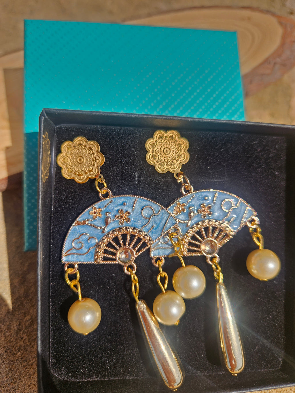 Pendientes en caja: flores doradas, medallones azules decorados y perlas con gotas