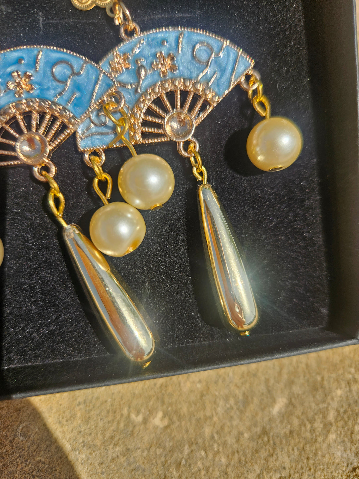 Detalle de pendientes: medallones azules, cadenas doradas, perlas y colgantes de gota