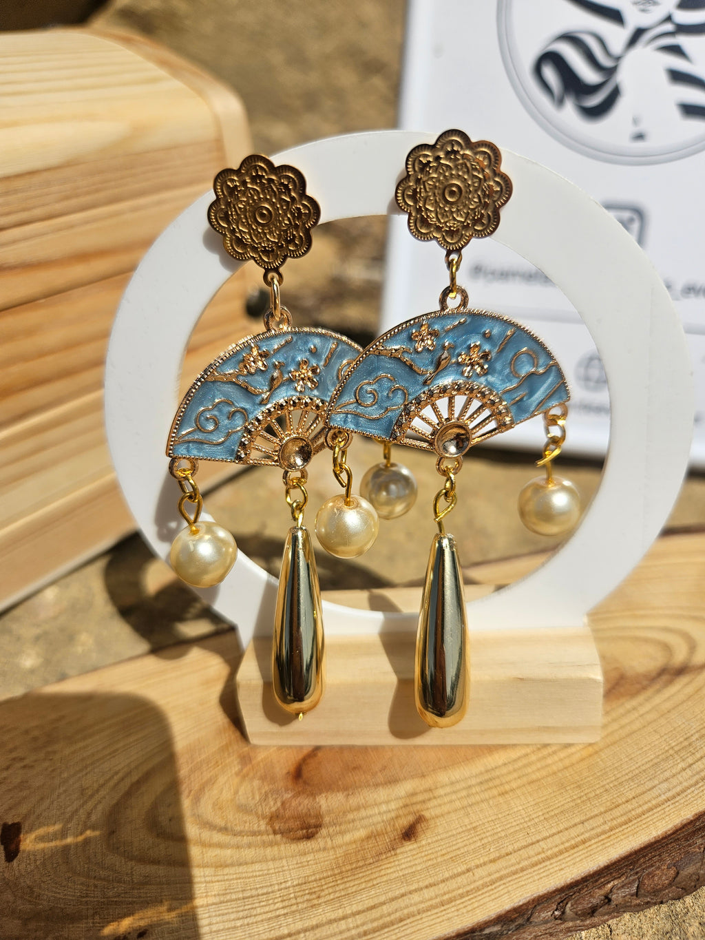 Pendientes colgantes: base dorada con medallón azul, perlas y dos gotas metálicas