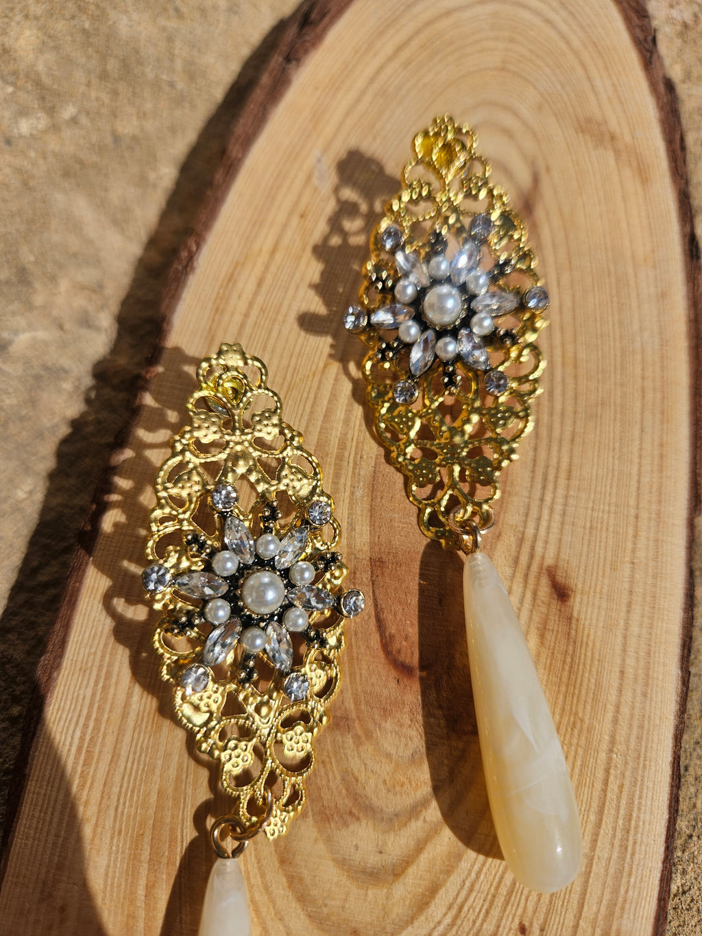 Pendientes dorados con flores de pedrería plateada y perlas, con gotas marfil