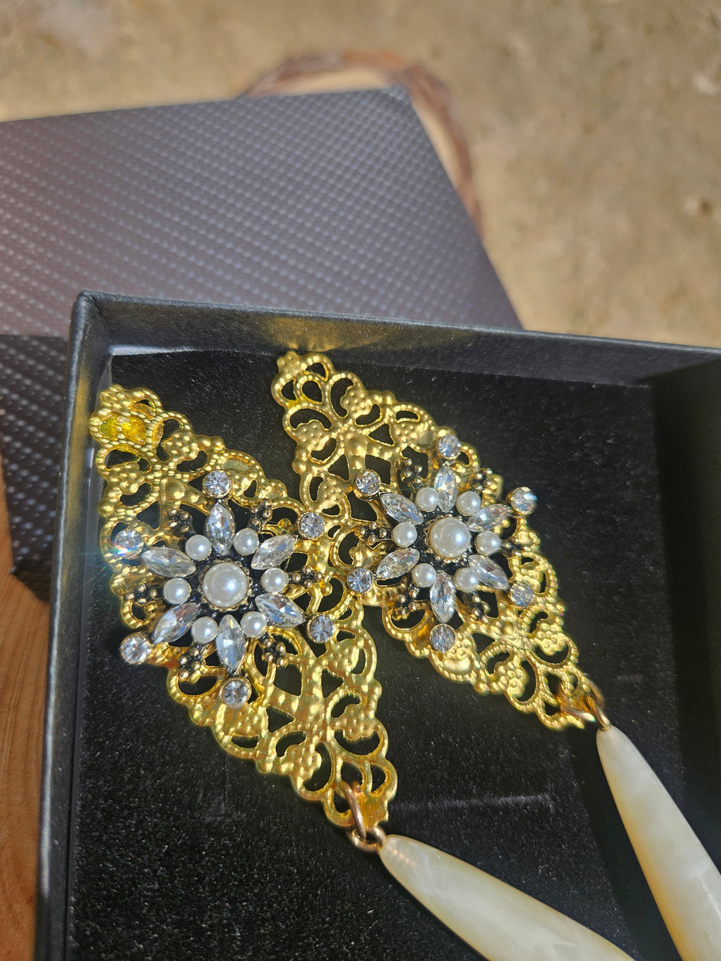 Detalle de pendientes dorados con cuentas, perlas y pedrería