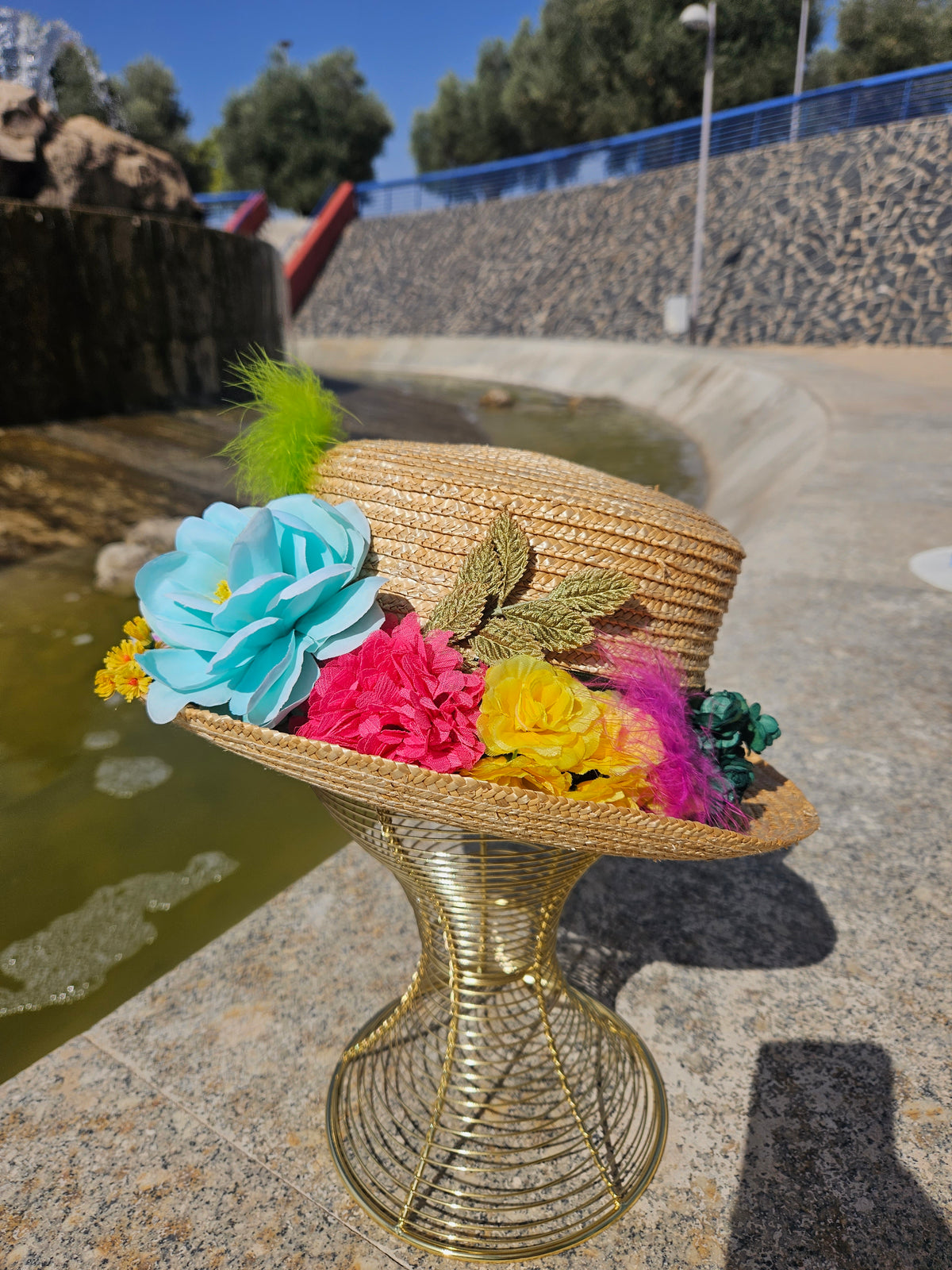 Sombrero de paja beige con flores azules, fucsia y amarillas y pluma verde