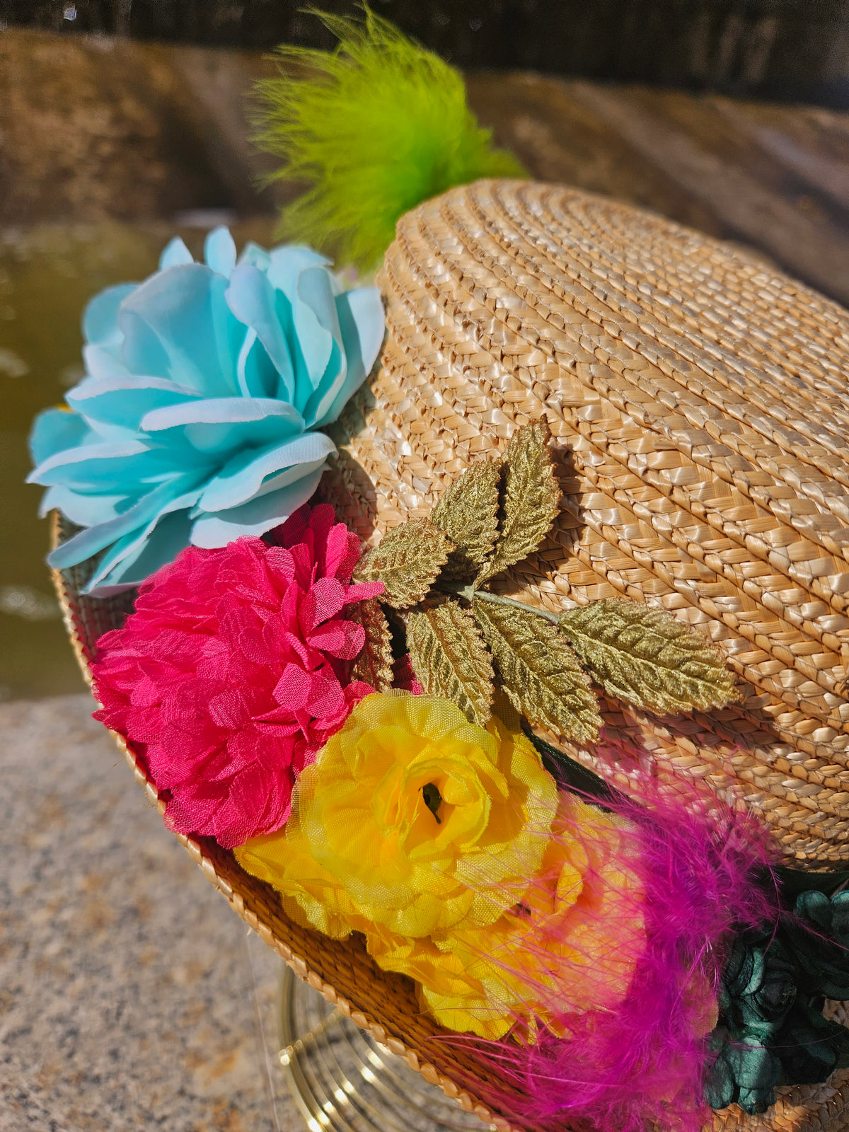 Sombrero de paja beige con flores azules, rojas, amarillas y pluma verde