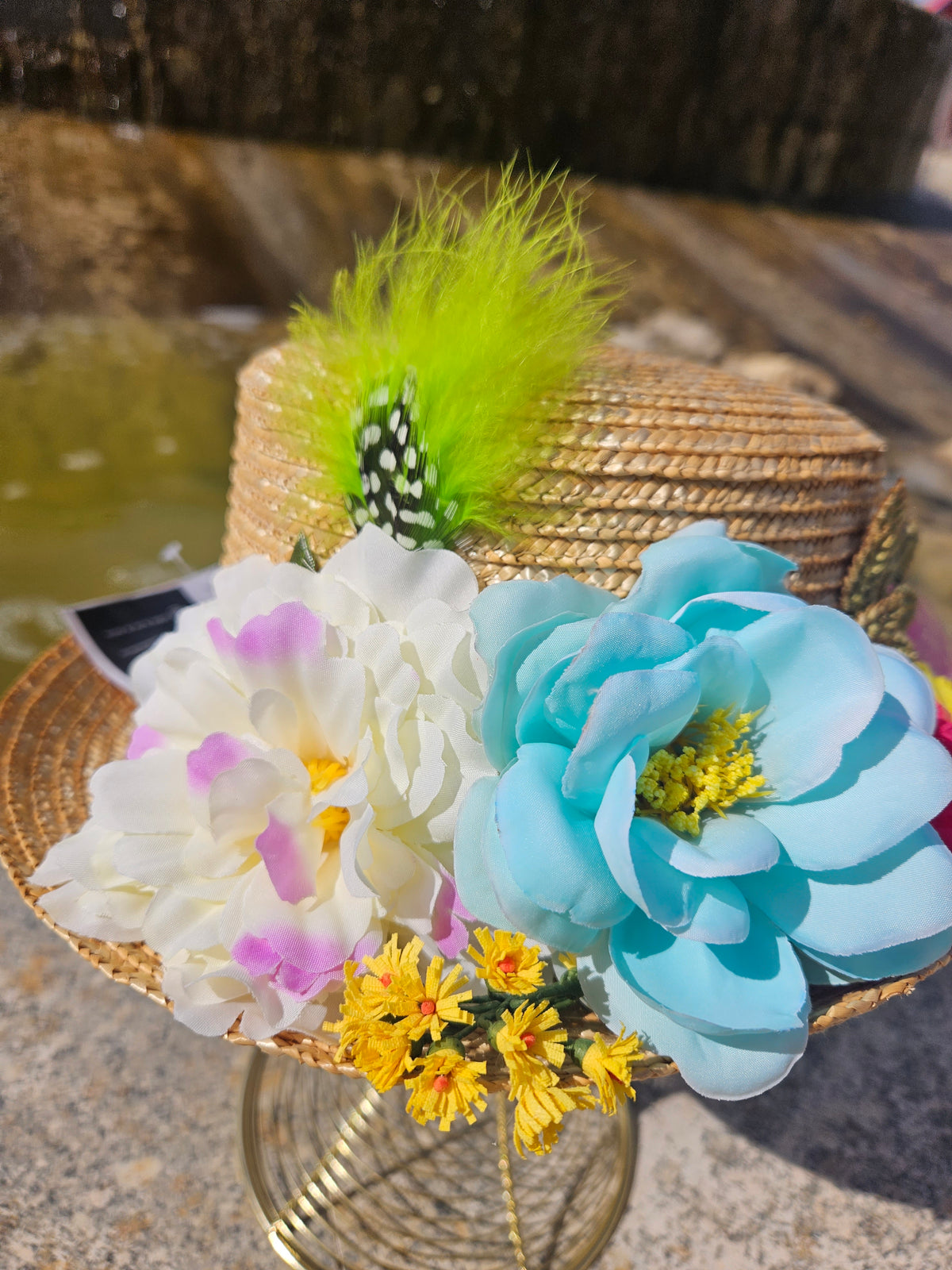 Sombrero de paja beige con flores blancas y azules, margaritas amarillas y pluma verde