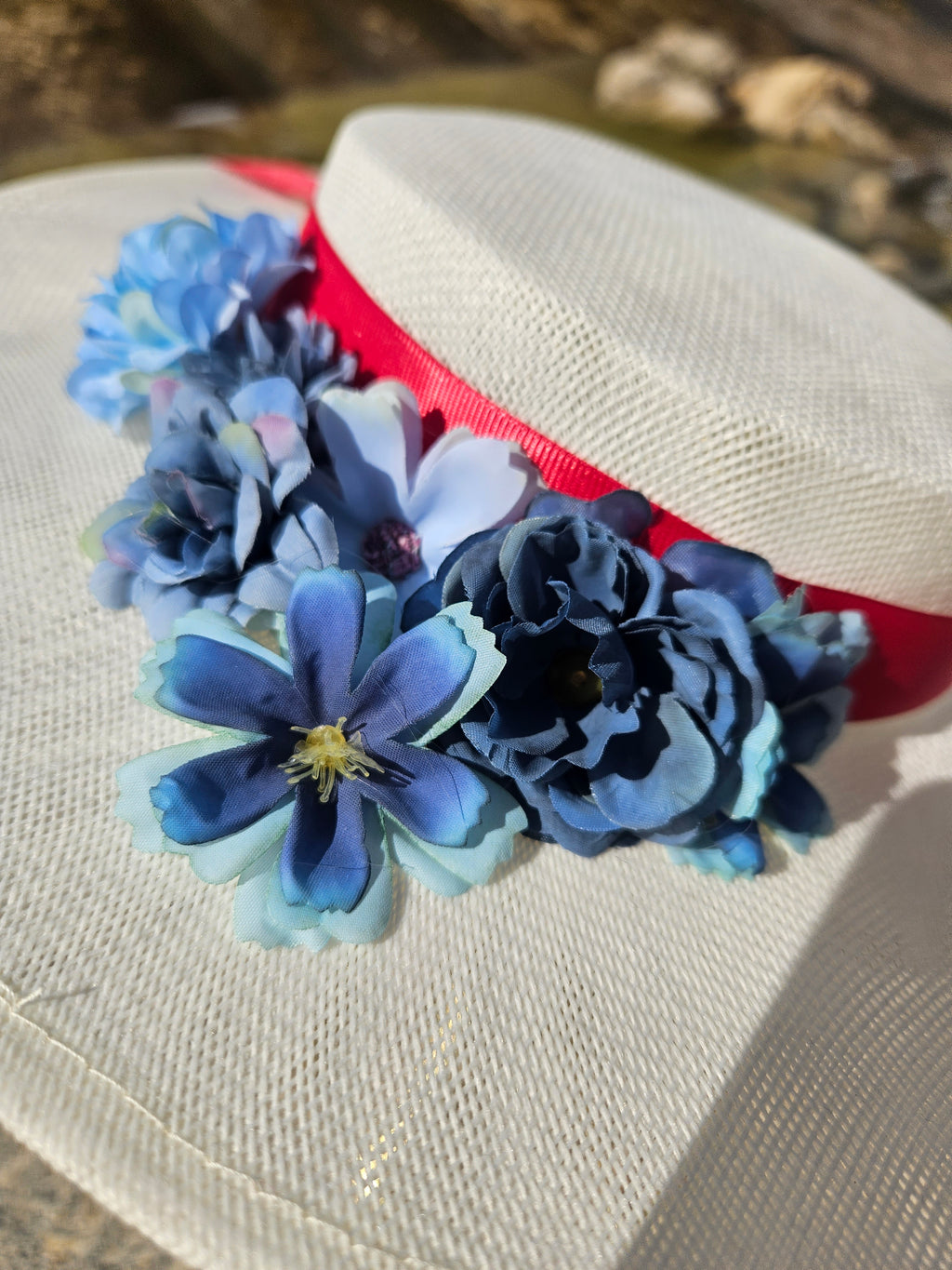 Pamela blanca con guirnalda de flores azules y cinta roja, detalle del adorno