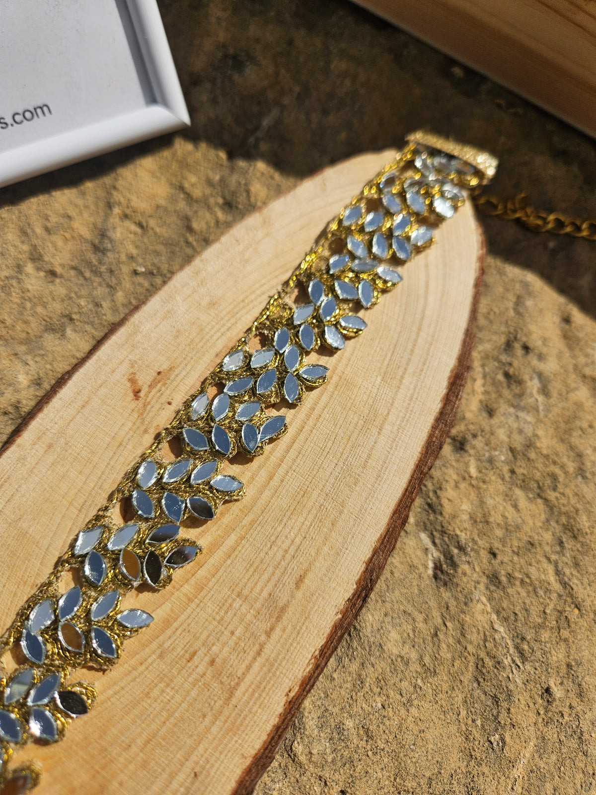 Gargantilla dorada con pedrería azul en motivo de hojas, diseño de cadena