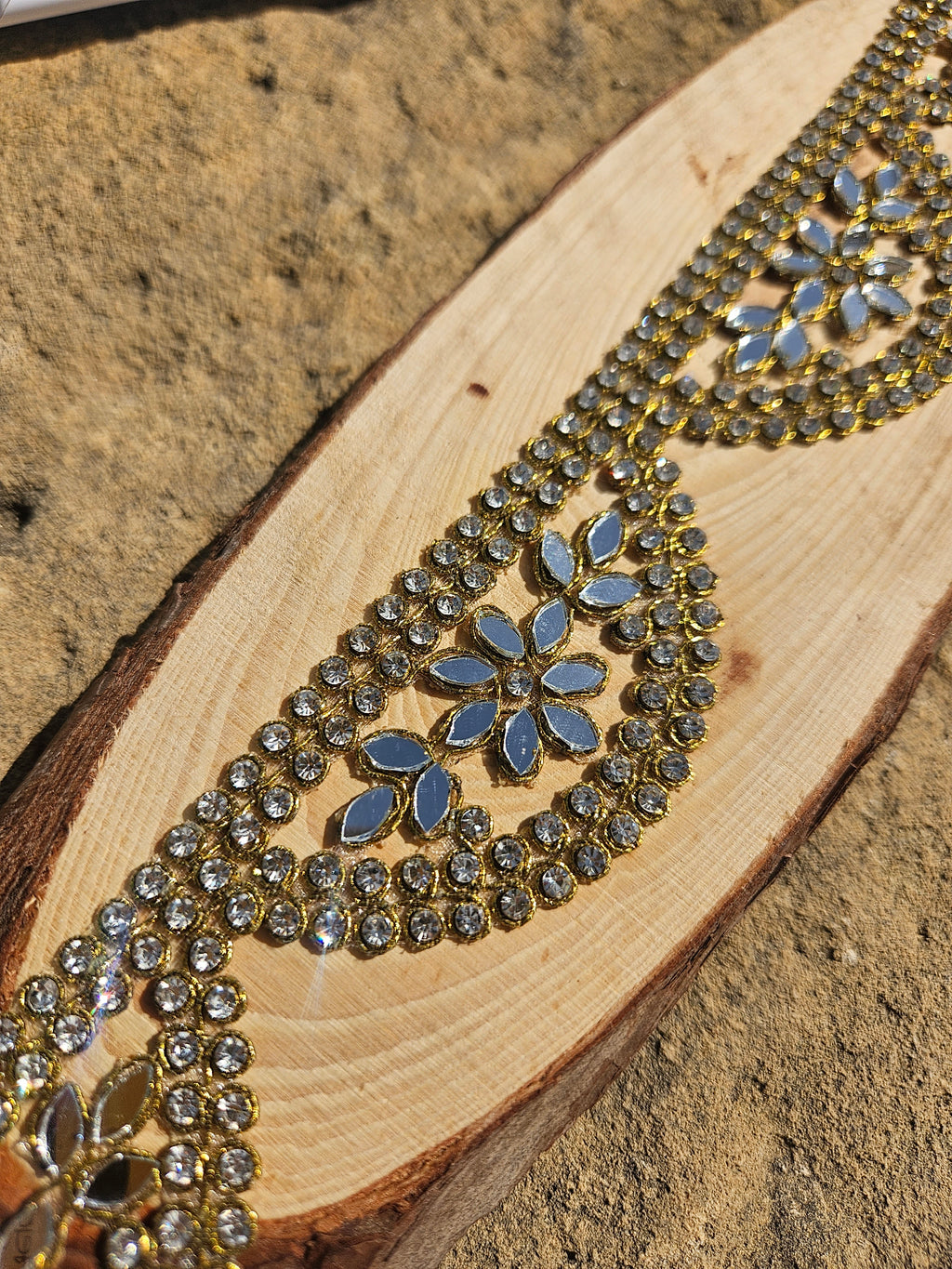 Close-up de gargantilla dorada con pedrería azul y motivo floral