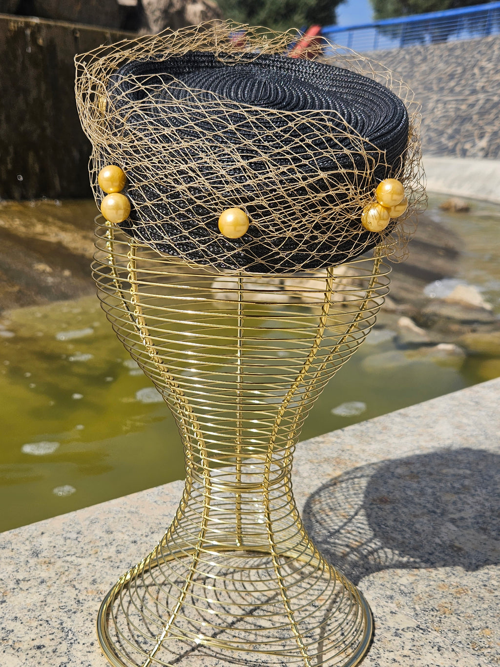 Sombrero fascinador negro con red dorada y cuentas esféricas decorativas