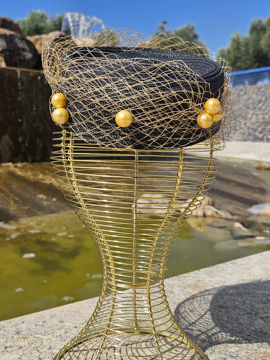 Sombrero fascinador negro con malla dorada y tres borlas de cuentas