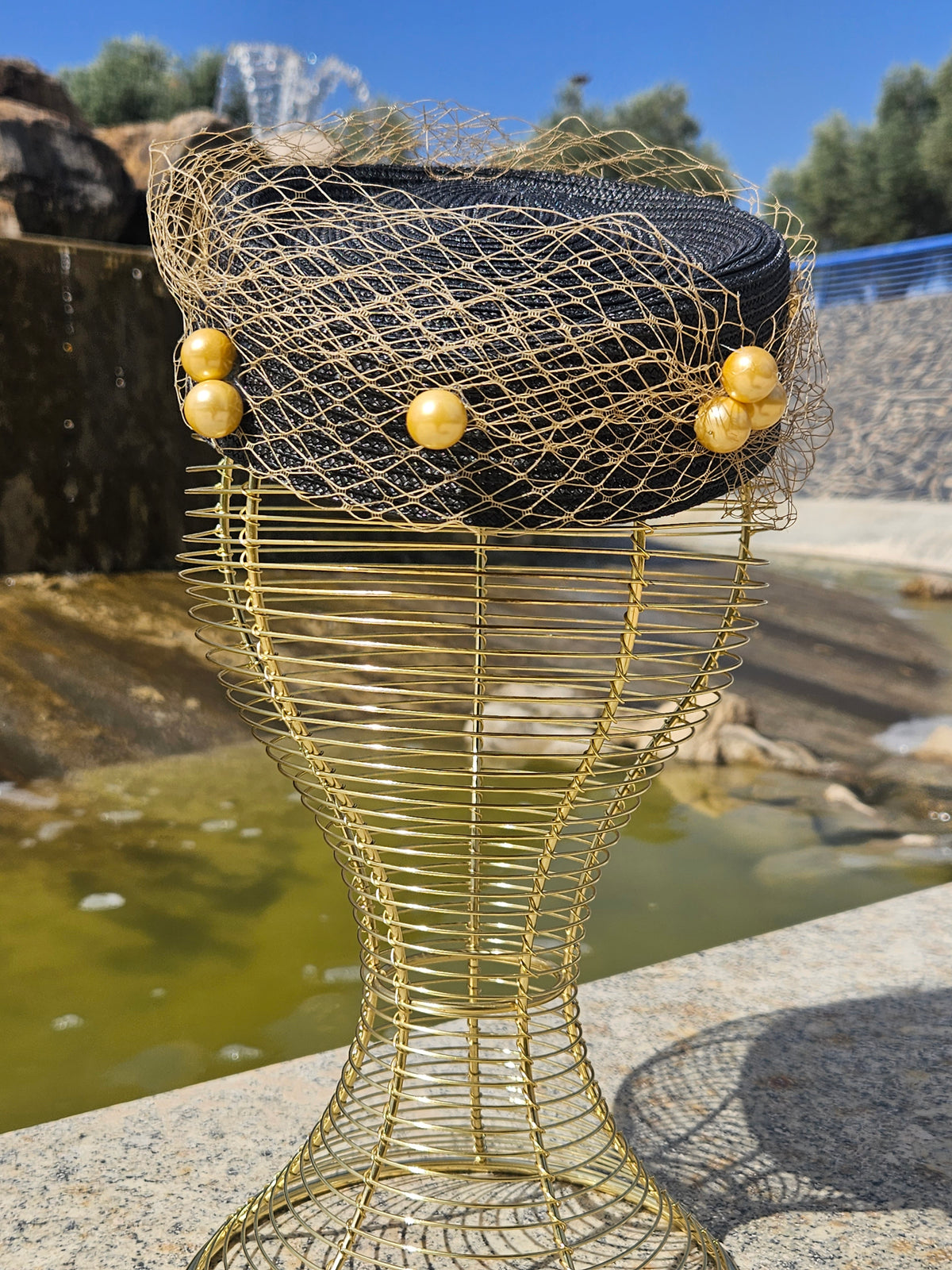 Sombrero fascinador negro con malla dorada y tres borlas de cuentas