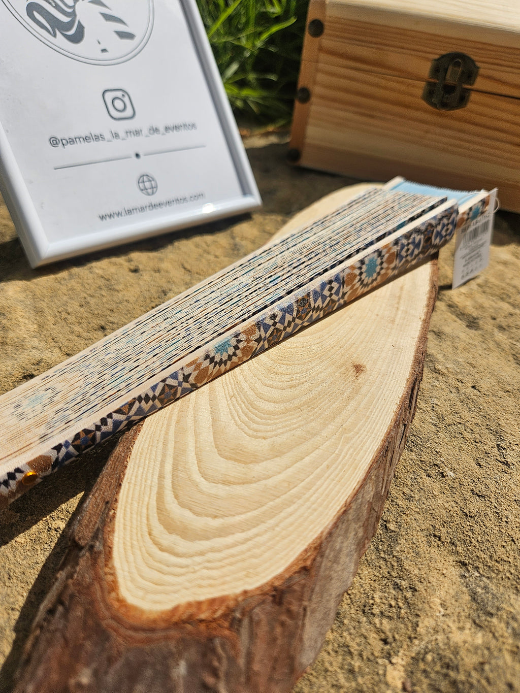 Abanico cerrado con patrón azul y crema, ribete geométrico y soporte de madera.