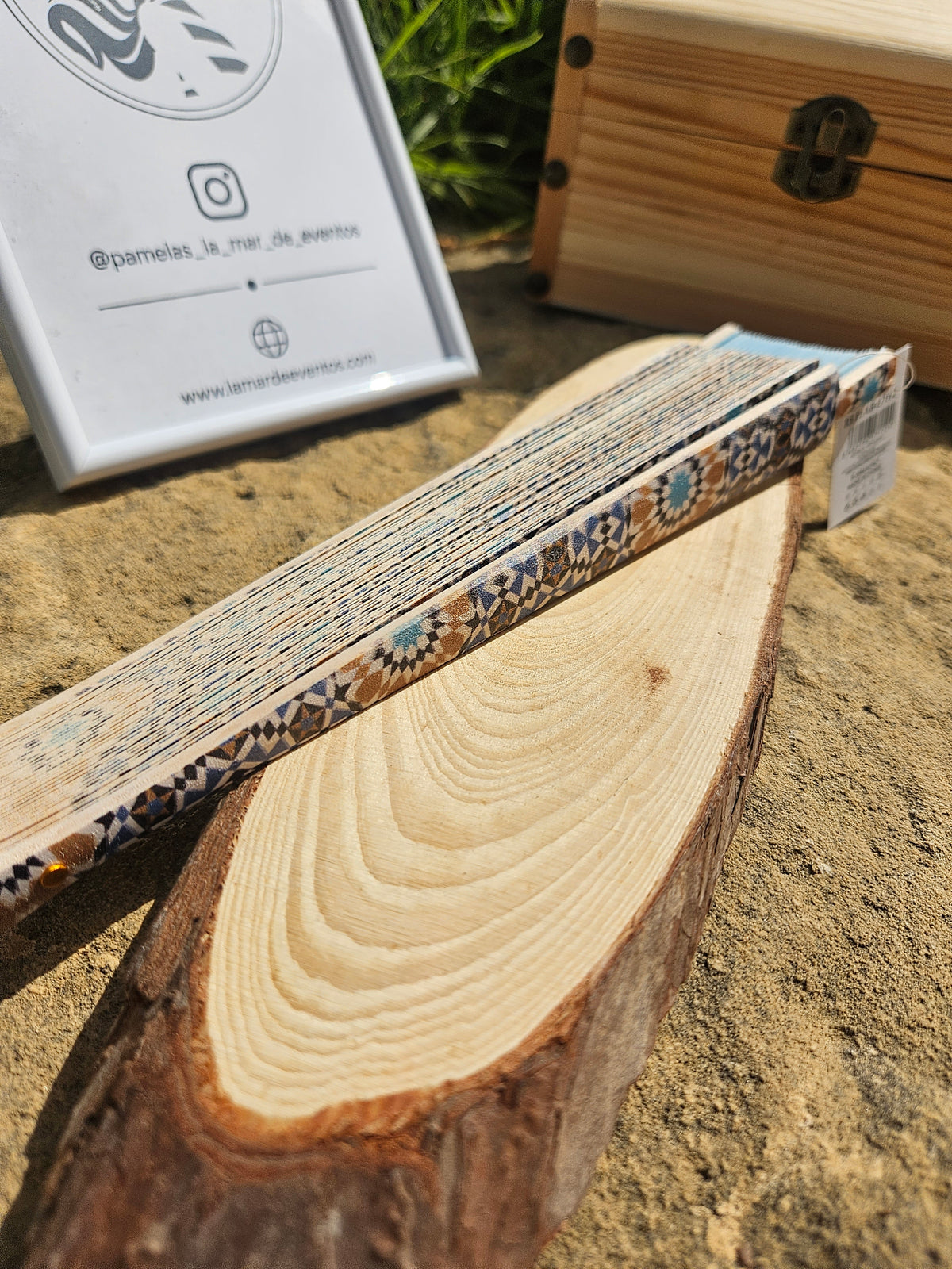 Abanico cerrado con patrón azul y crema, ribete geométrico y soporte de madera.