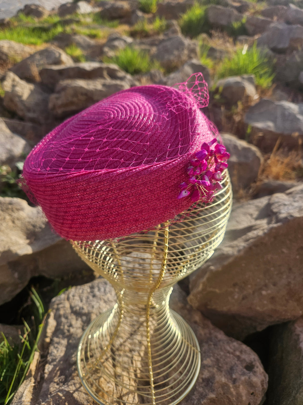 Sombrero fucsia con velo de red y adorno floral brillante en el lateral