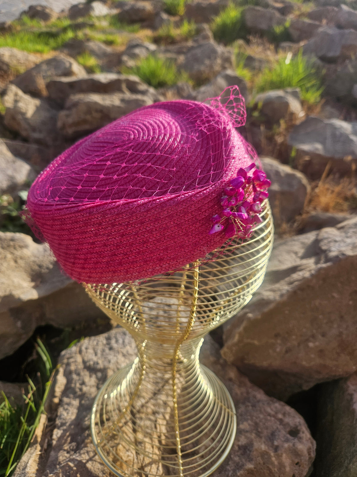 Sombrero fucsia con velo de red y adorno floral brillante en el lateral