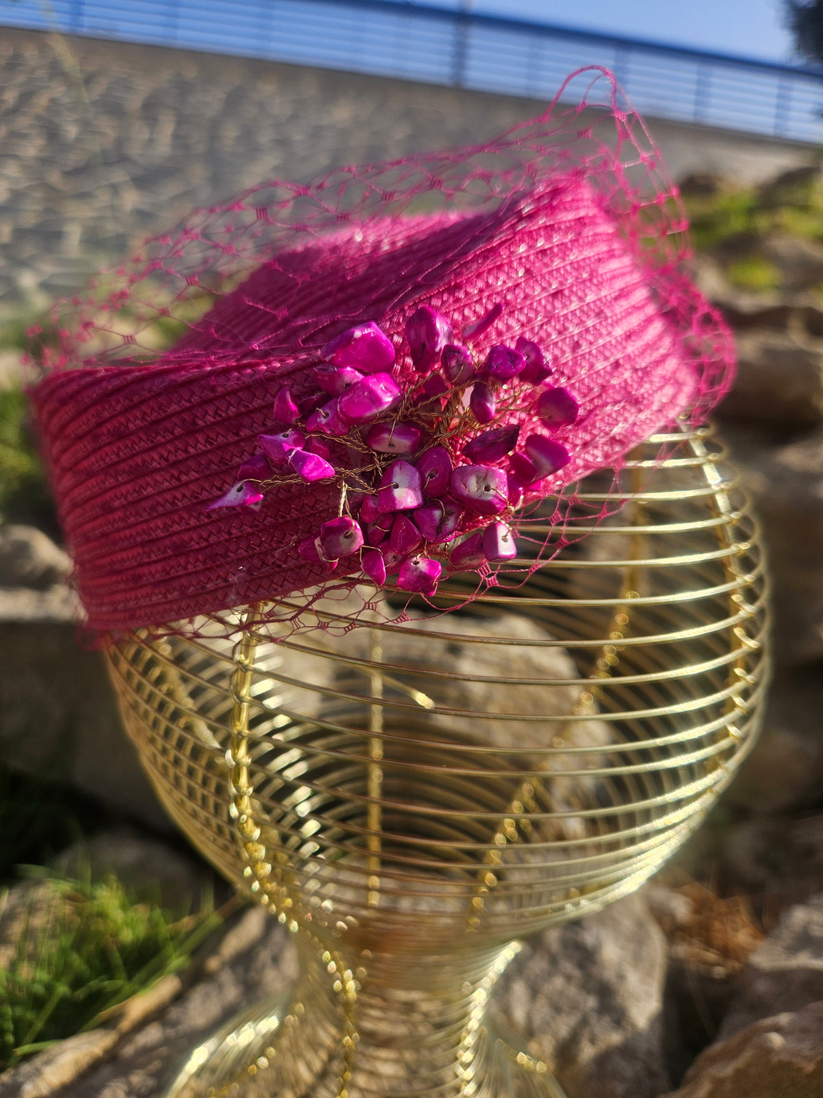 Sombrero fucsia con gran adorno floral brillante y velo de malla sobre maniquí