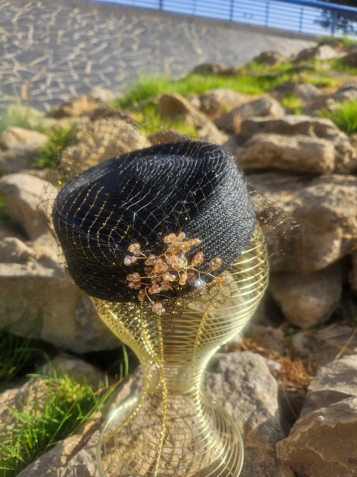 Sombrero de malla negro con adorno floral dorado en la copa