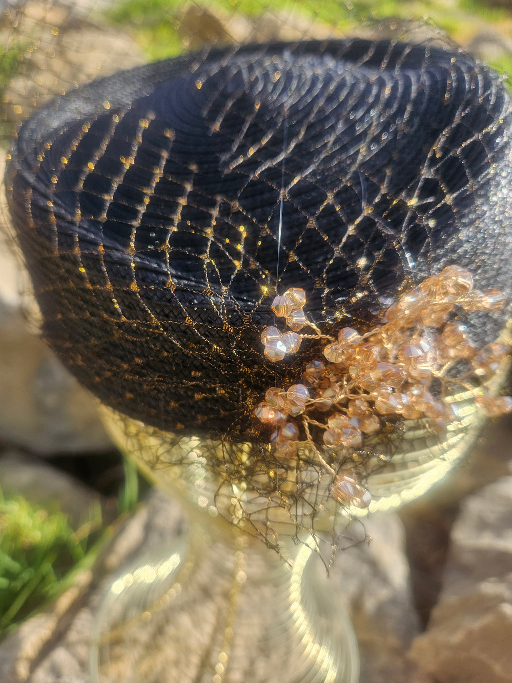 Sombrero de malla negro con pedrería y flor dorada en primer plano