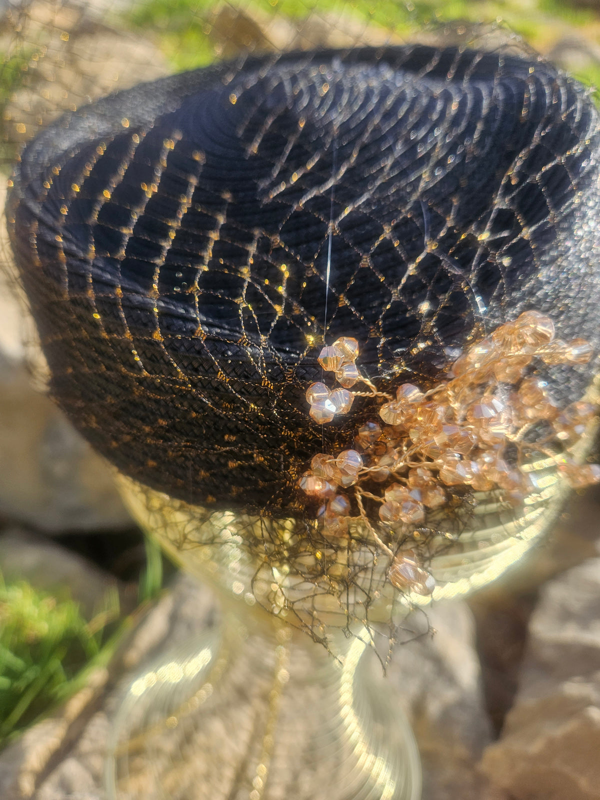 Sombrero de malla negro con pedrería y flor dorada en primer plano