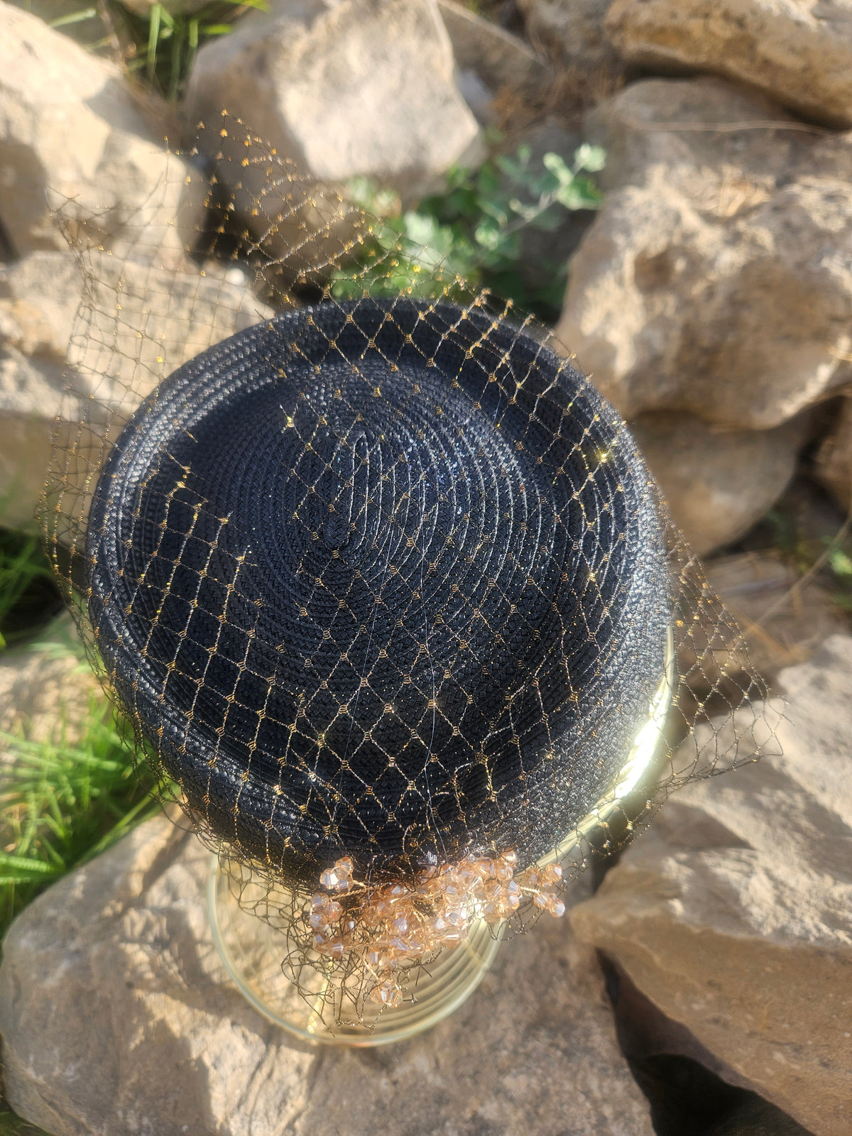 Sombrero de malla negra con flor dorada en la parte frontal