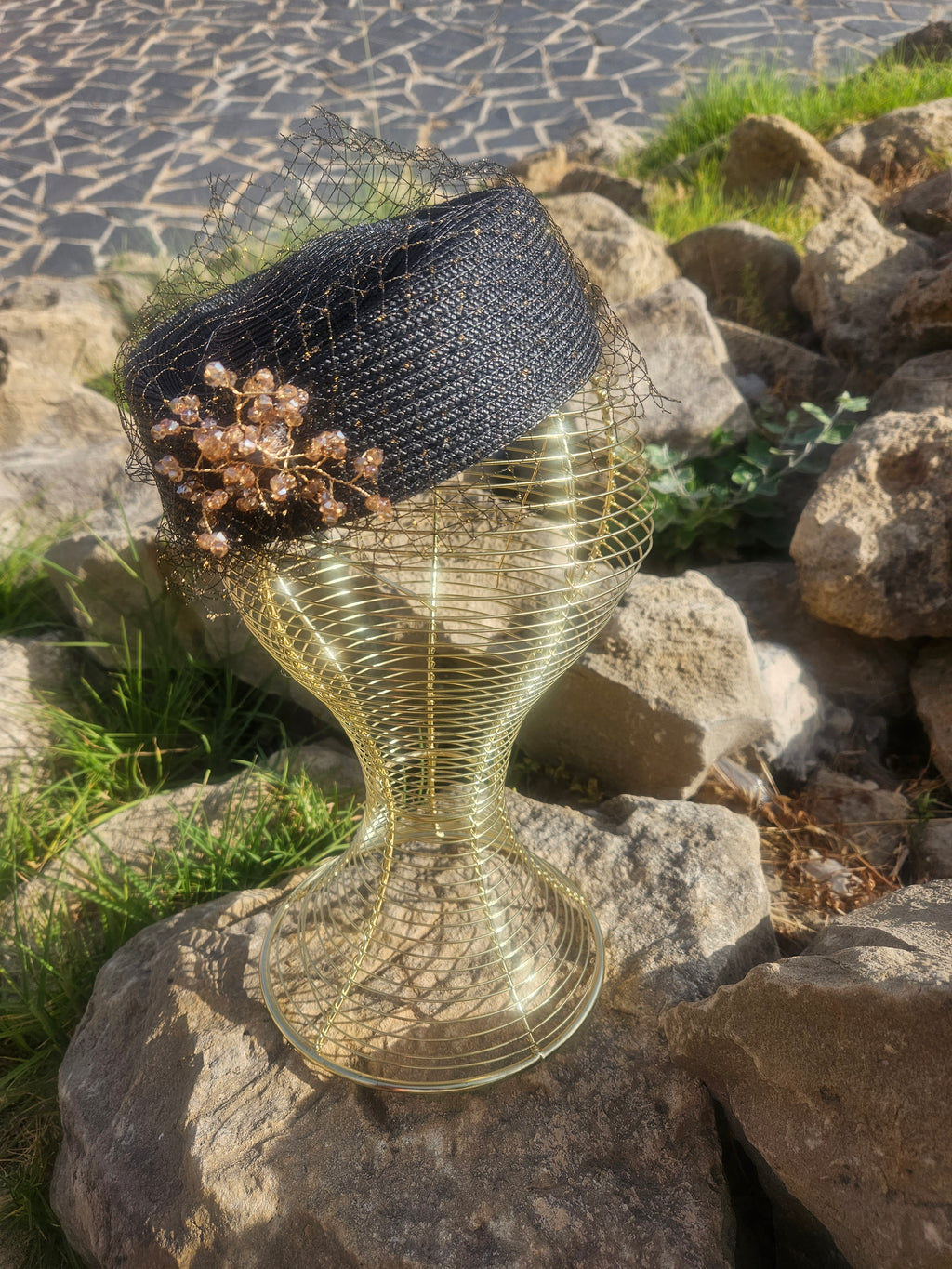 Sombrero de malla negro con adorno floral dorado y base en espiral