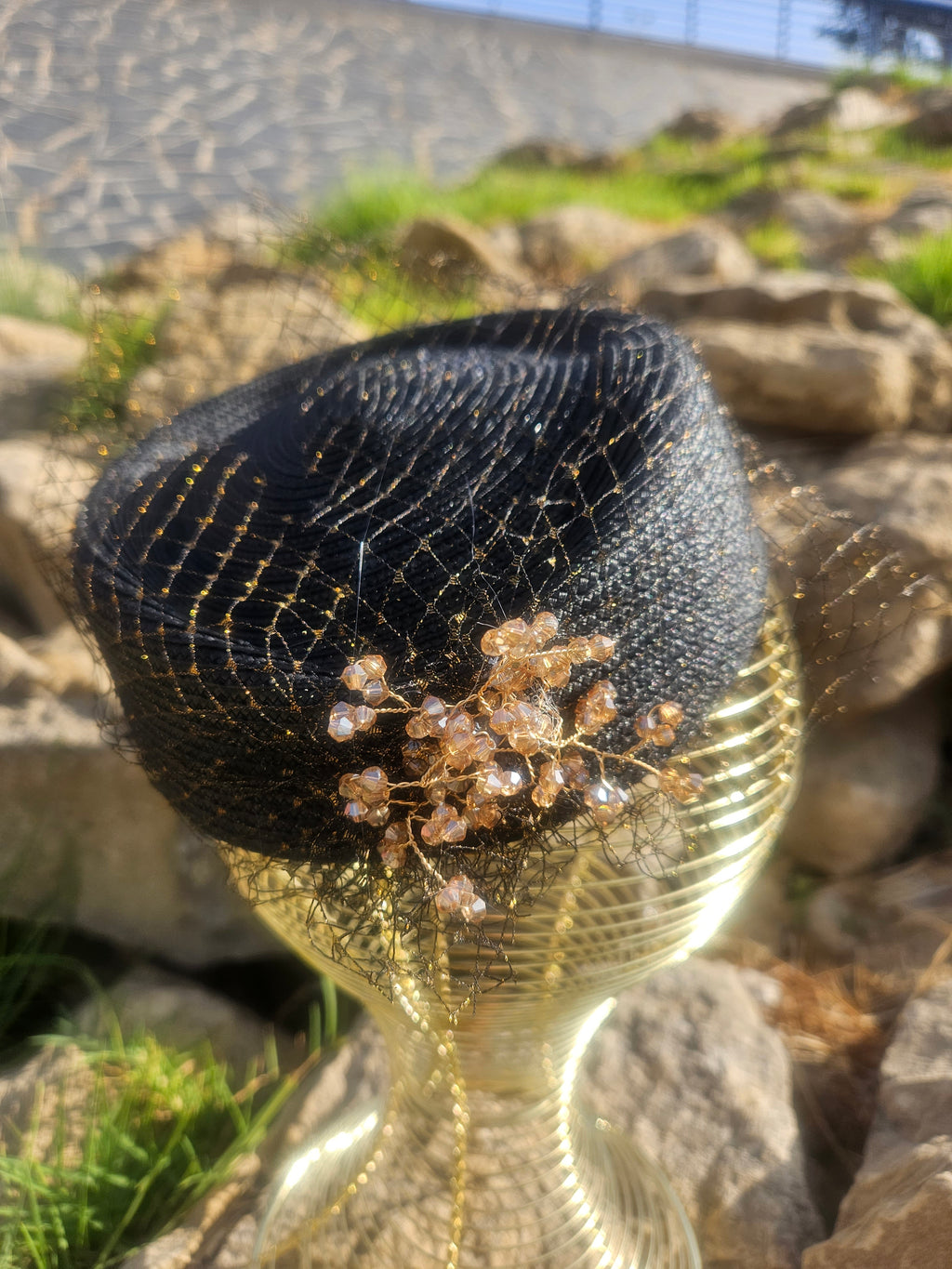 Sombrero de malla negro con flor dorada sobre la copa y ala corta