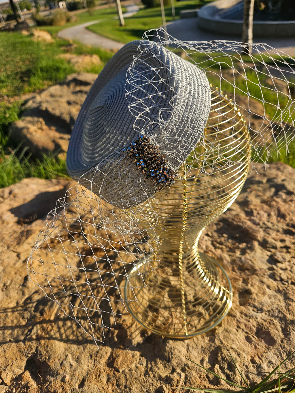 Sombrero azul con malla dorada en espiral, velo y banda frontal de cuentas negras.