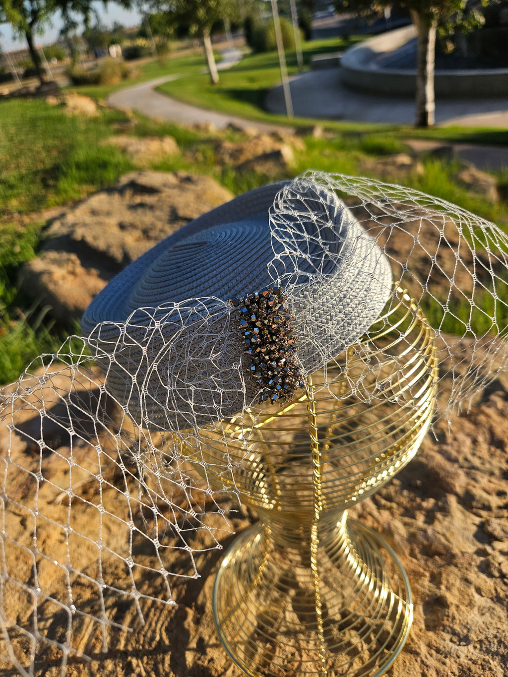 Sombrero azul marino con velo de malla y detalle central de cuentas negras.