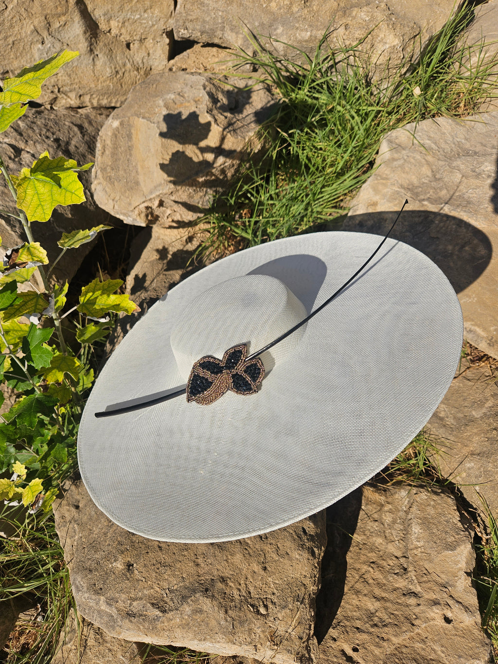 Sombrero de ala ancha claro con diadema negra y adorno tipo mariposa bordado