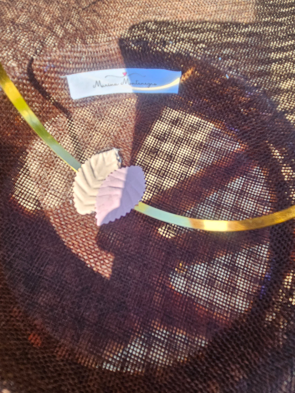 Detalle de pamela marrón con etiqueta azul y lazo, con adorno floral naranja
