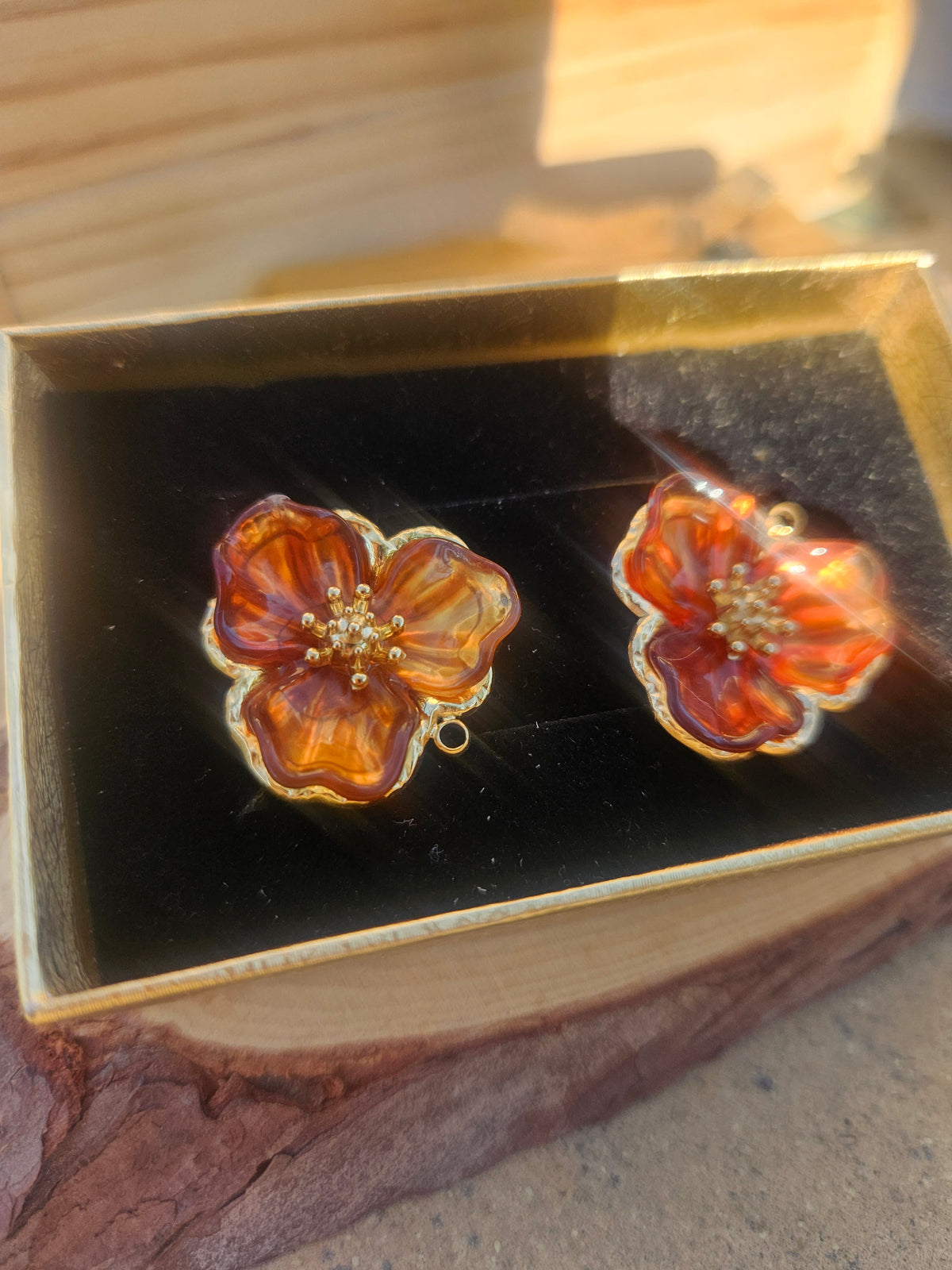 Pendientes tipo flor con esmalte ámbar translúcido y detalles dorados, cierre de aro.