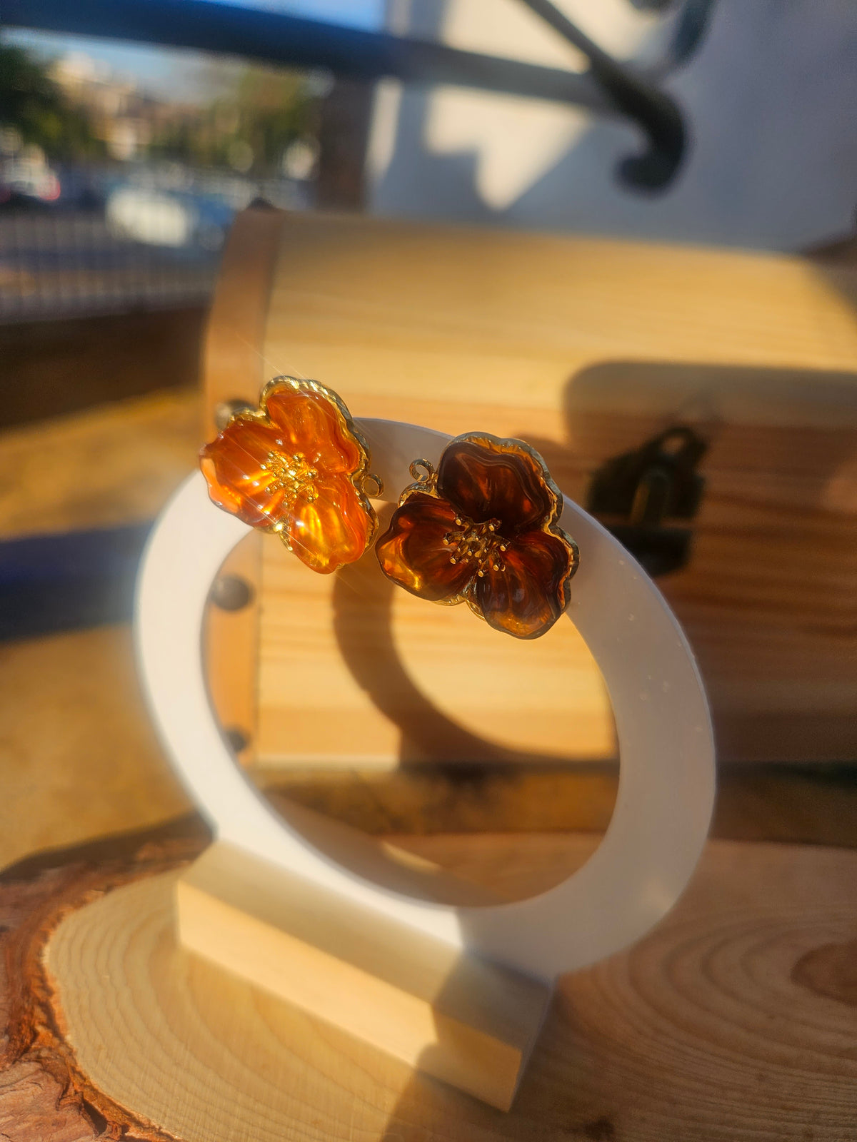 Pendientes flor ámbar con brillo en el centro y borde dorado; montura sobre aro grande.