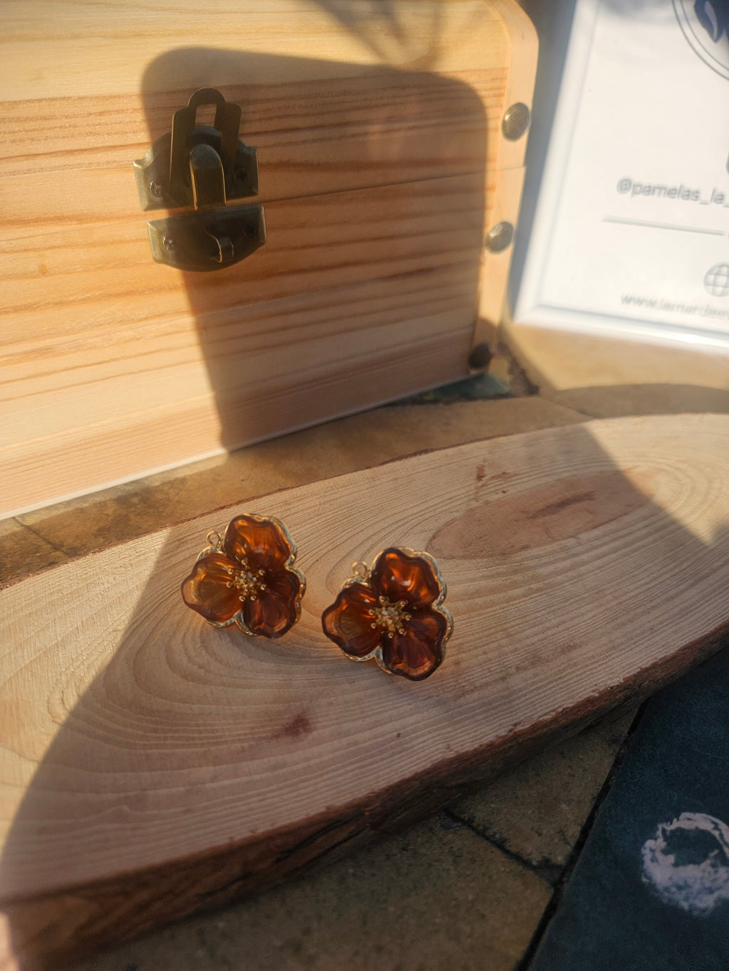Pendientes flor ámbar de cristal con detalles dorados sobre madera; cierre trasero visible.