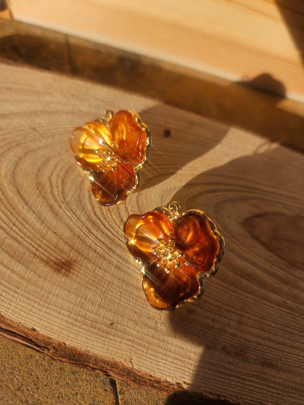 Pendientes flor ámbar en relieve, tonos dorados intensos y centro con pedrería discreta.