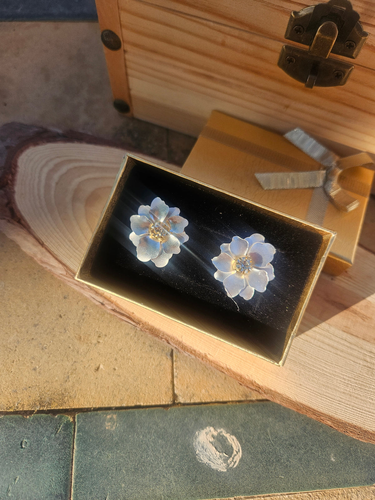Pendientes de flor azul con centro dorado, sobre estuche negro.