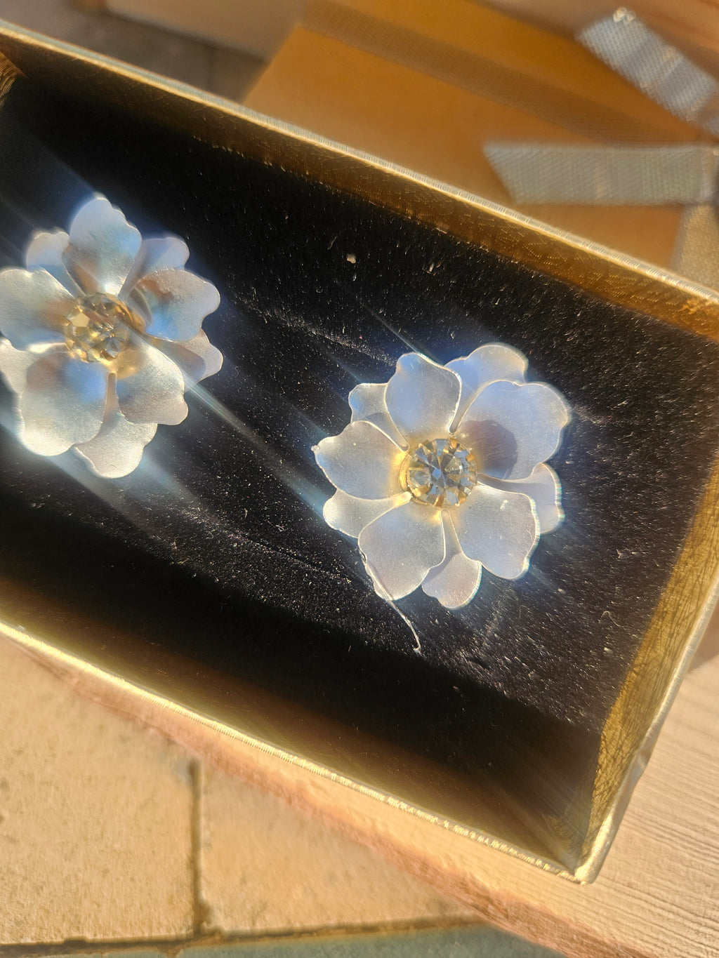 Pendientes con dos flores azules y centro dorado, con brillo radial.