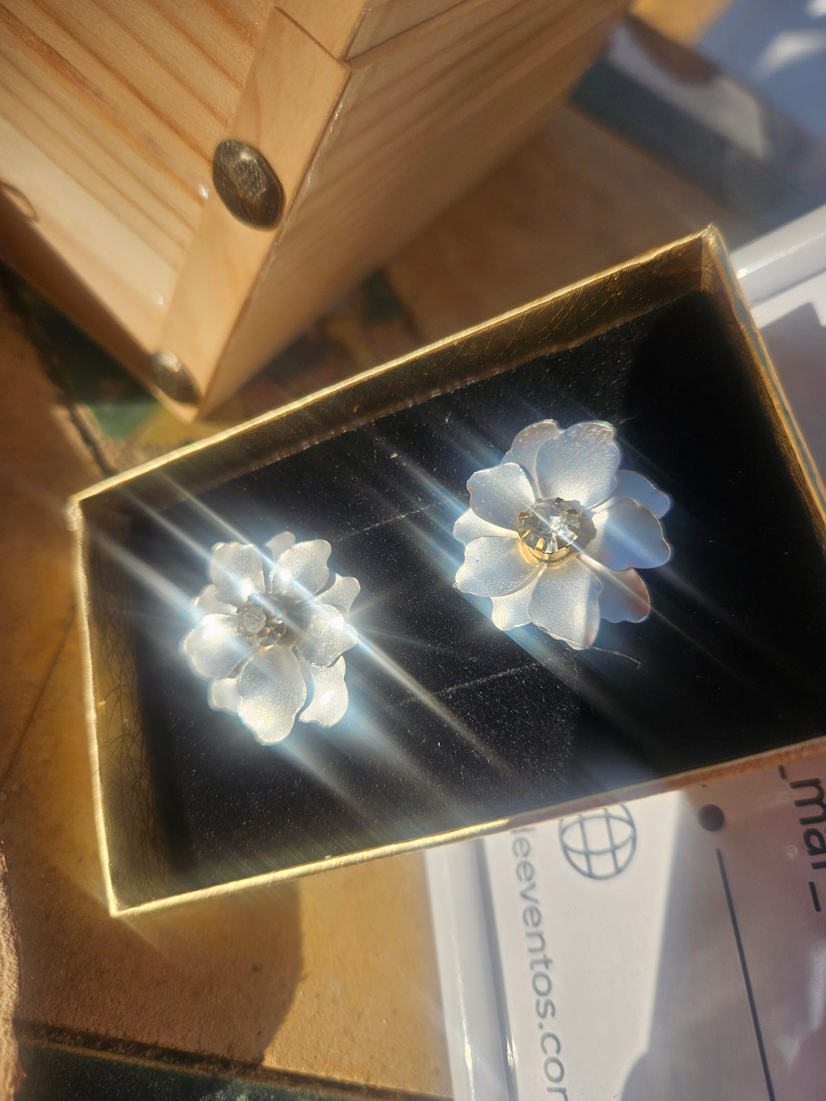 Pendientes de flores azules y centro dorado, vistos de cerca en caja.