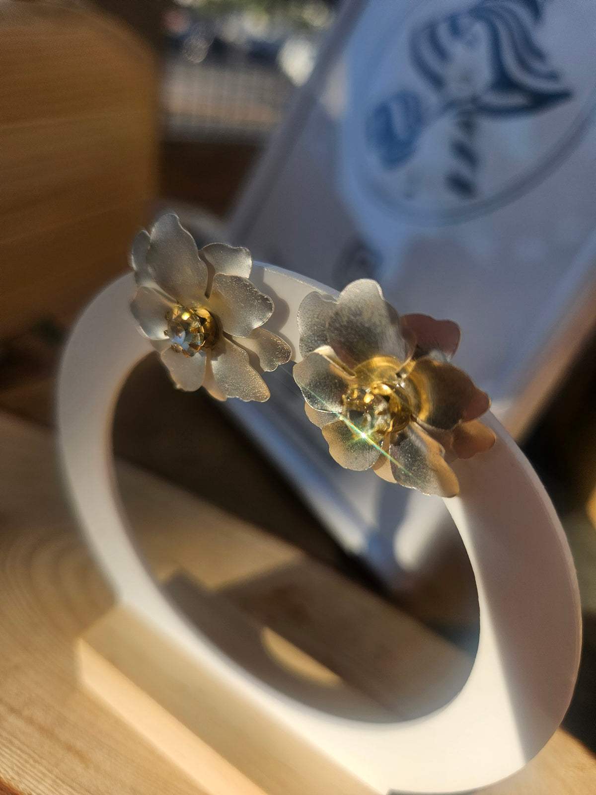 Pendientes de flor azul con centro dorado, sobre soporte en forma de aro.