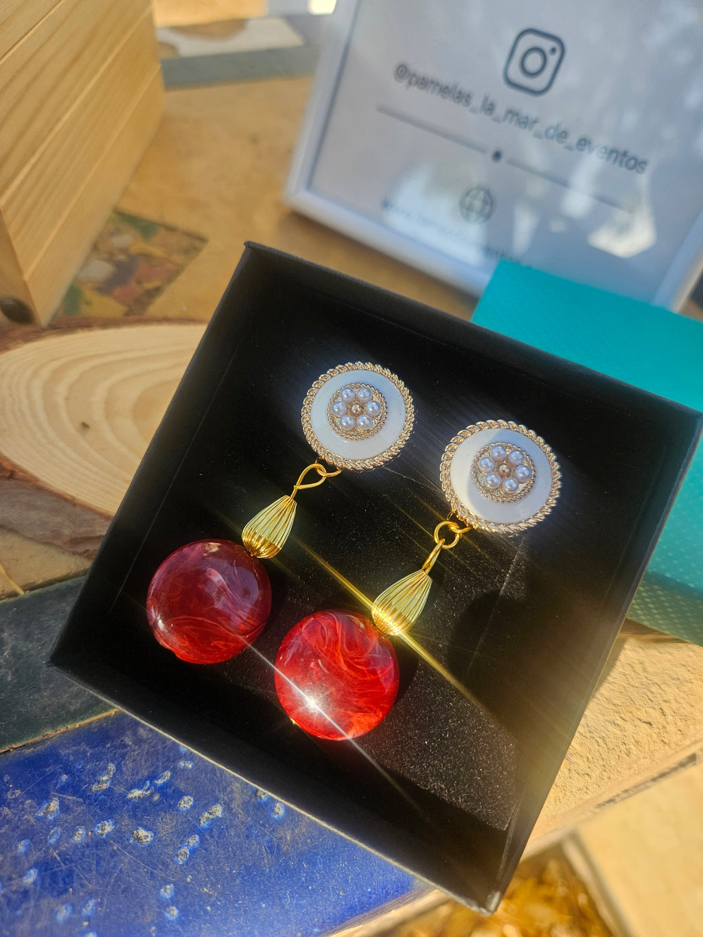 Pendientes colgantes con aro dorado y borla, y piedras rojas tipo lágrima.