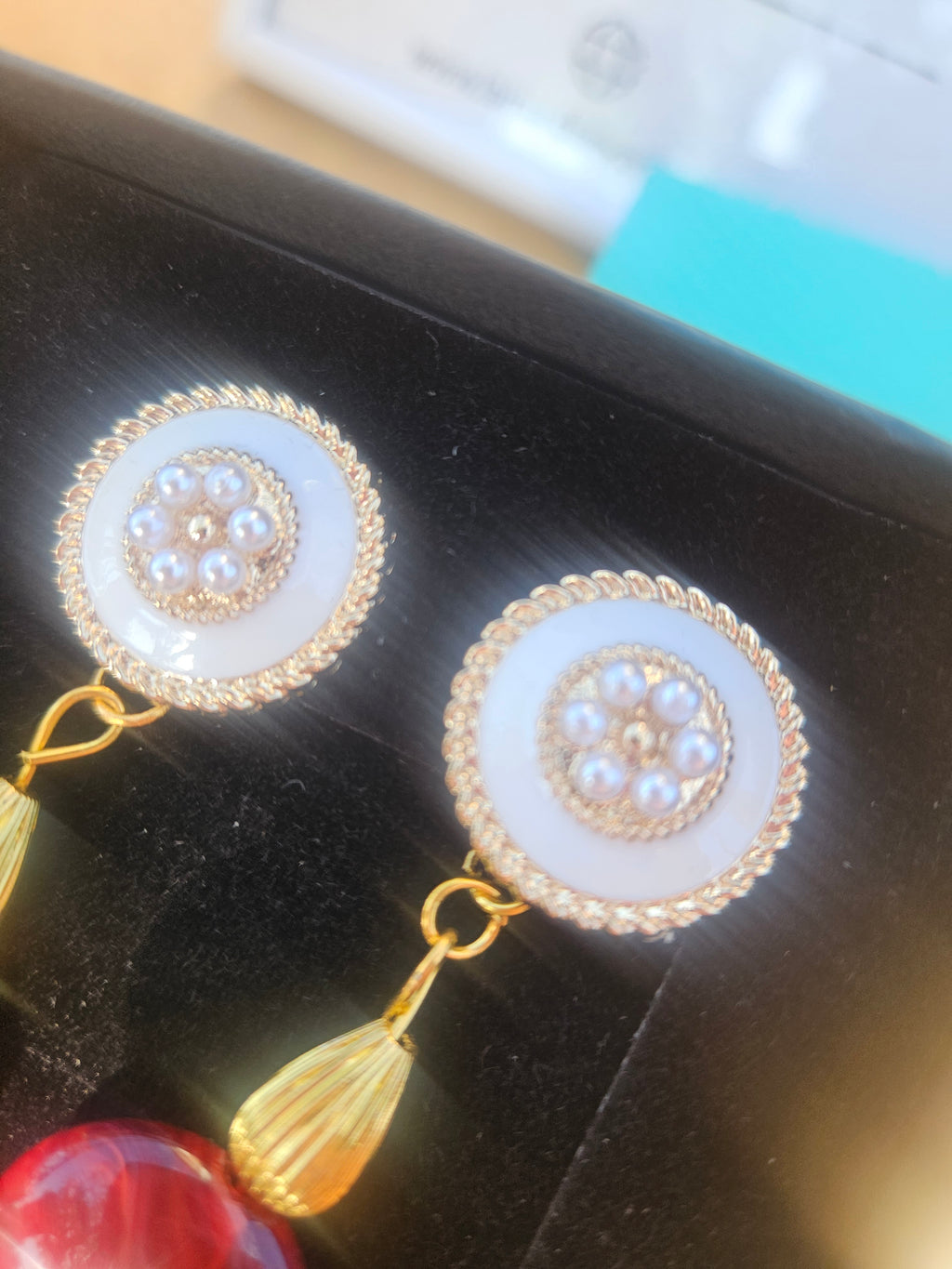 Par de pendientes circulares con detalles dorados y piedras claras, con borla colgante.