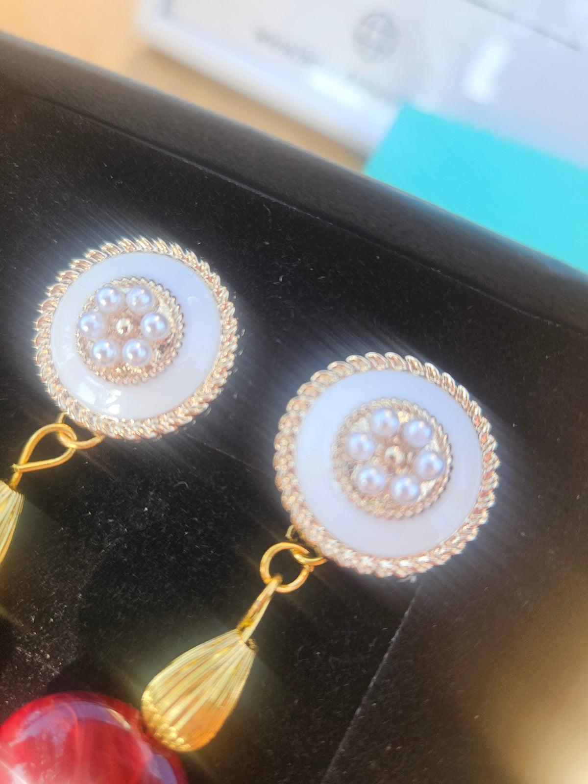Par de pendientes circulares con detalles dorados y piedras claras, con borla colgante.